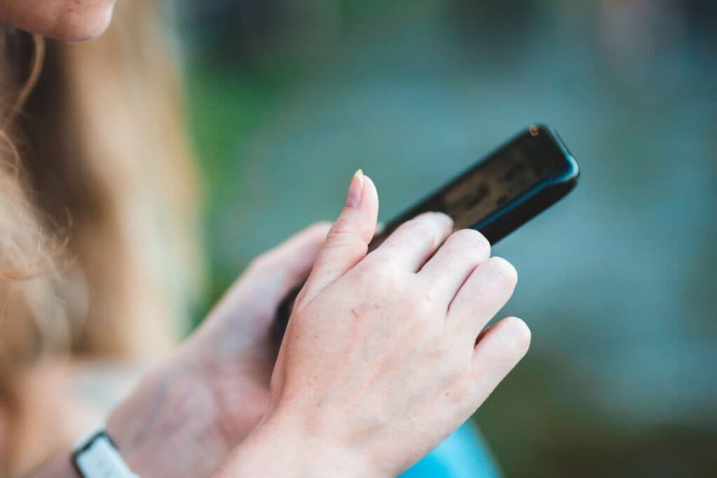 Persona revisando información en un teléfono móvil, enfatizando la importancia de verificar fuentes oficiales para prevenir desinformación.