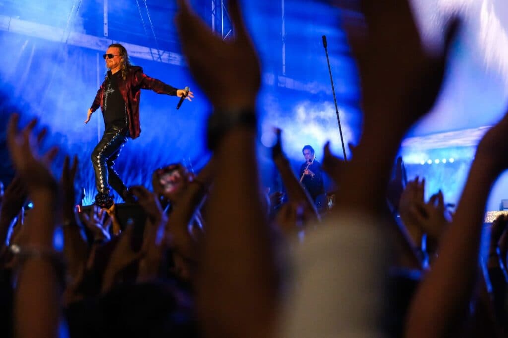 Vocalista de Maná enérgico sobre el escenario, mientras el público aplaude y levanta las manos en La Minerva, Guadalajara.
