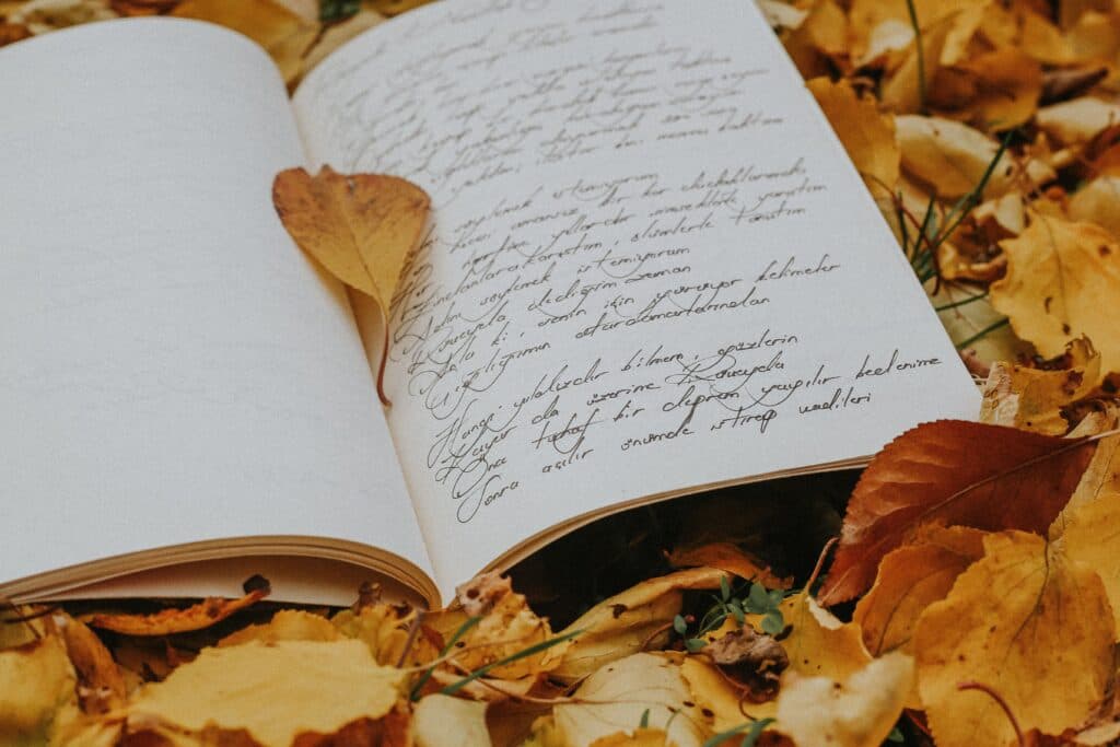 Poesía escrita en un cuaderno abierto sobre un fondo de hojas secas, simbolizando la creatividad literaria en el Premio