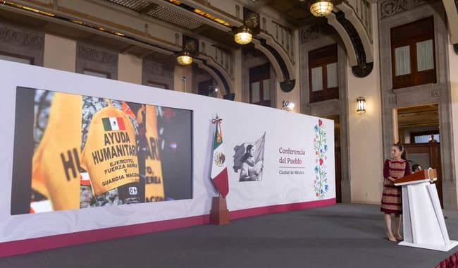 Claudia Sheinbaum Pardo presenta la ayuda humanitaria de México en conferencia, con un fondo que muestra un cartel de "Ayuda Humanitaria".