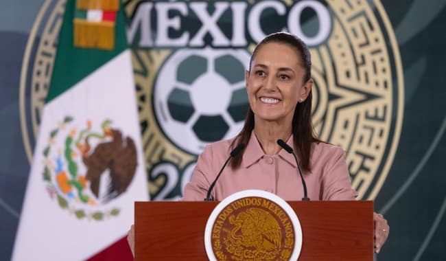 Claudia Sheinbaum Pardo sonríe mientras entrega boletos del Mundial 2026 a la ciudadanía, con el logo del evento de fondo.