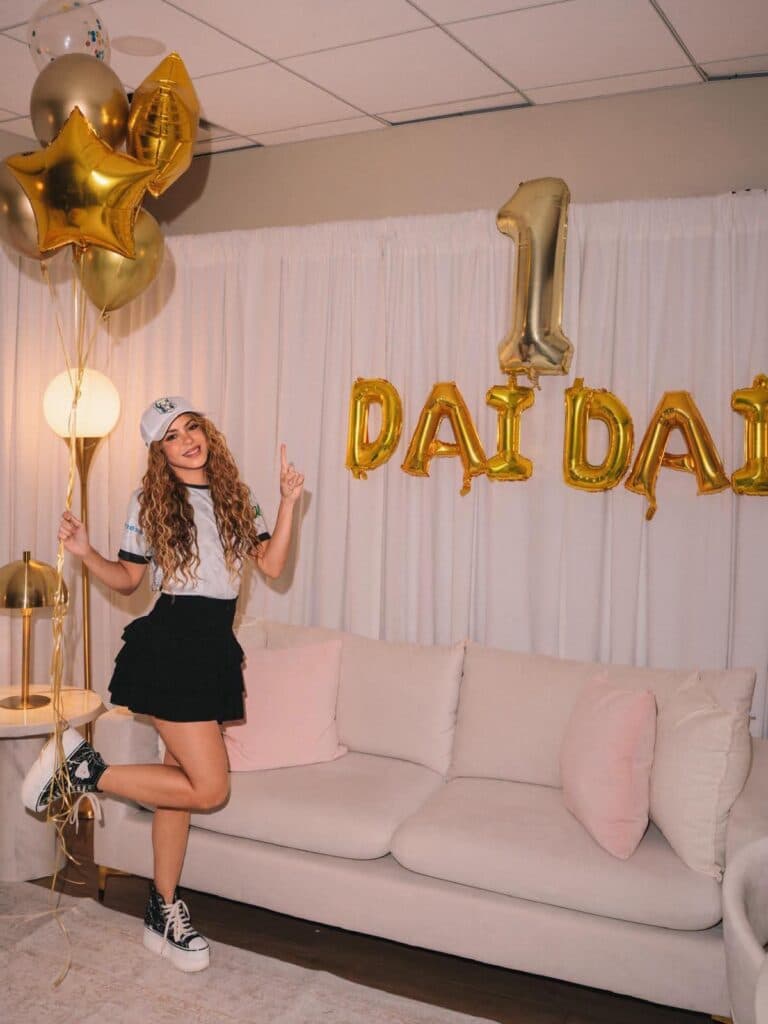 Shakira celebra el éxito de "Dai Dai" en Spotify, posando con globos dorados y una decoración festiva en su hogar.