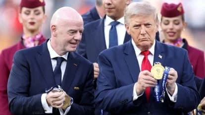 Gianni Infantino y Donald Trump sostienen medallas en un evento, mientras otros asistentes observan, simbolizando la controversia en el futbol.