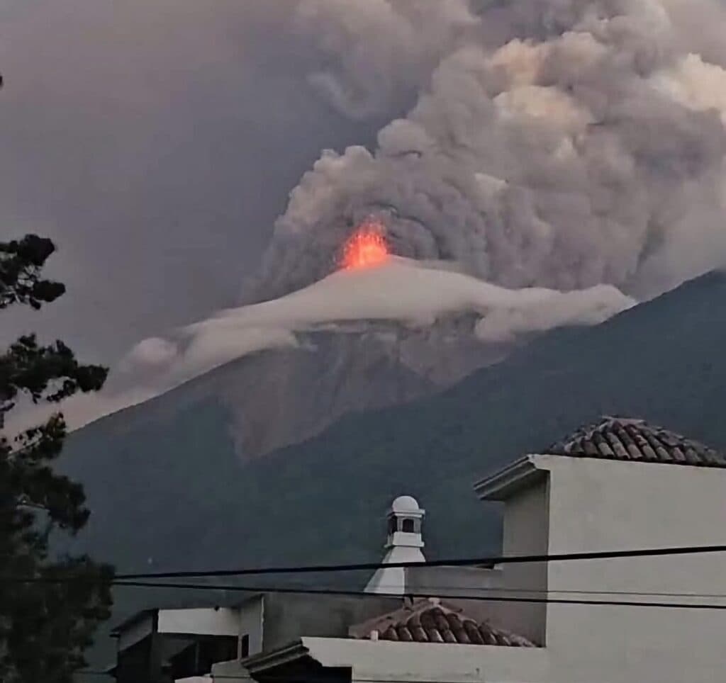 El Volcán de Fuego emite lava y ceniza, con una intensa actividad eruptiva visible desde edificios cercanos en Guatemala.