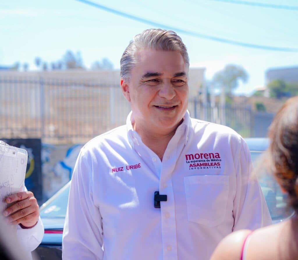 Ruiz Uribe sonríe mientras interactúa con vecinos en Lomas Taurinas, promoviendo los resultados de Claudia Sheinbaum en Tijuana.