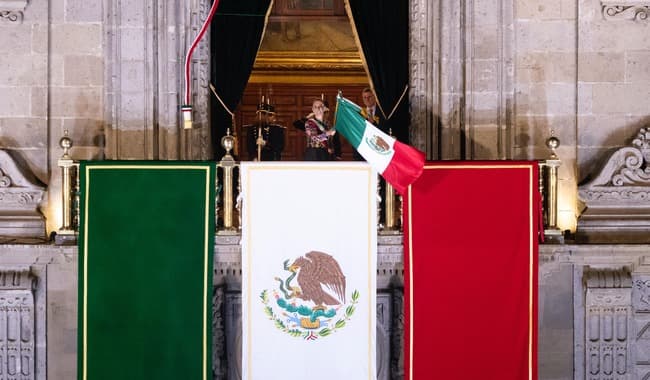 Claudia Sheinbaum en el balcón de Palacio Nacional durante el Grito de Independencia, con banderas de México en el Zócalo.