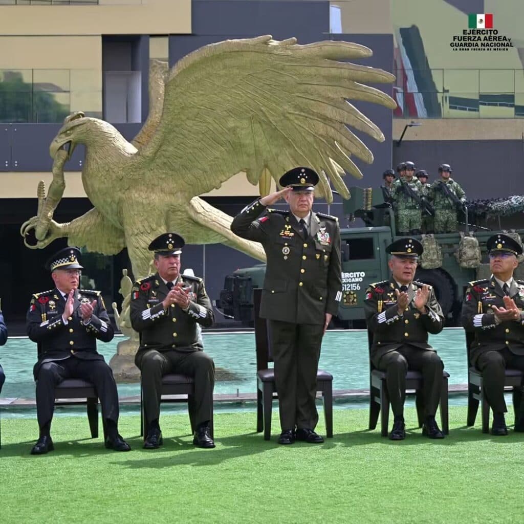 Ceremonia del 205 aniversario de la Sedena, con el general Trevilla en el centro, saludando, y otros altos mandos aplaudiendo.